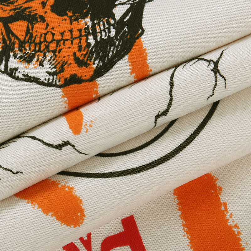 Close-up of textured fabric featuring bold skull graphic and orange accents, perfect for trendy casual wear.