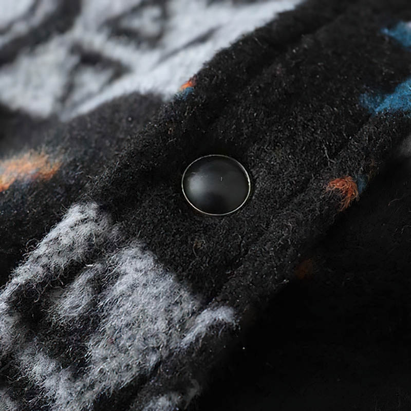 Close-up of men's geometric graphic shirt showing fabric detail and button, highlighting retro style.