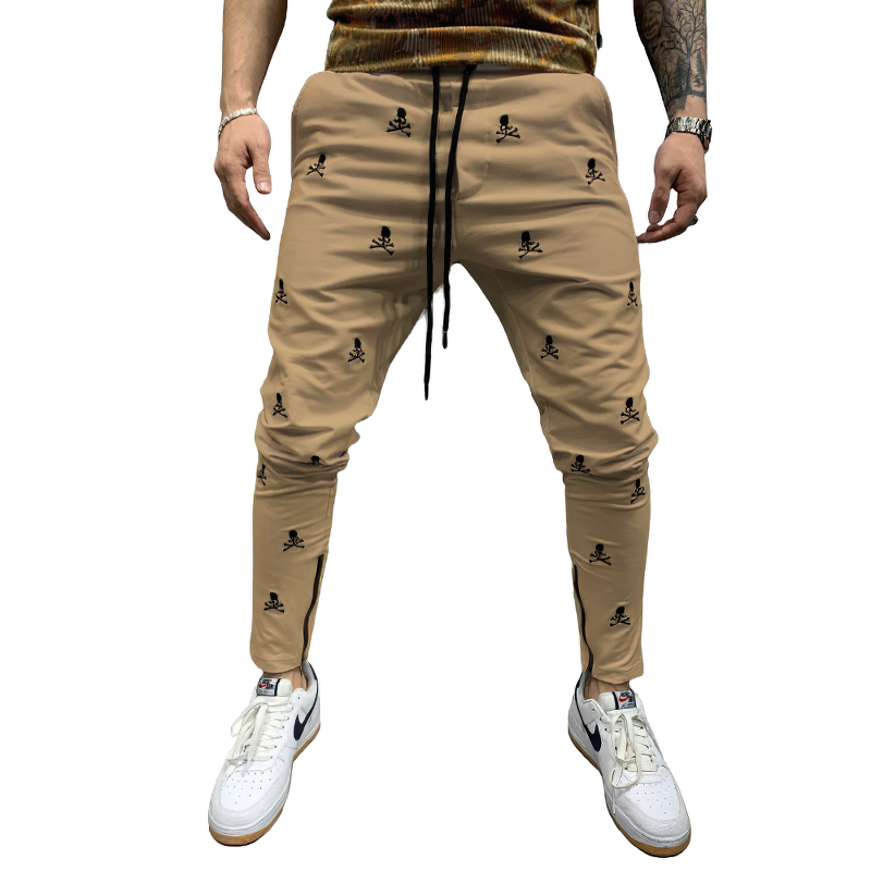 Casual men's lace-up pants in khaki with skull print, featuring elastic waistband and tapered fit, styled with white sneakers.