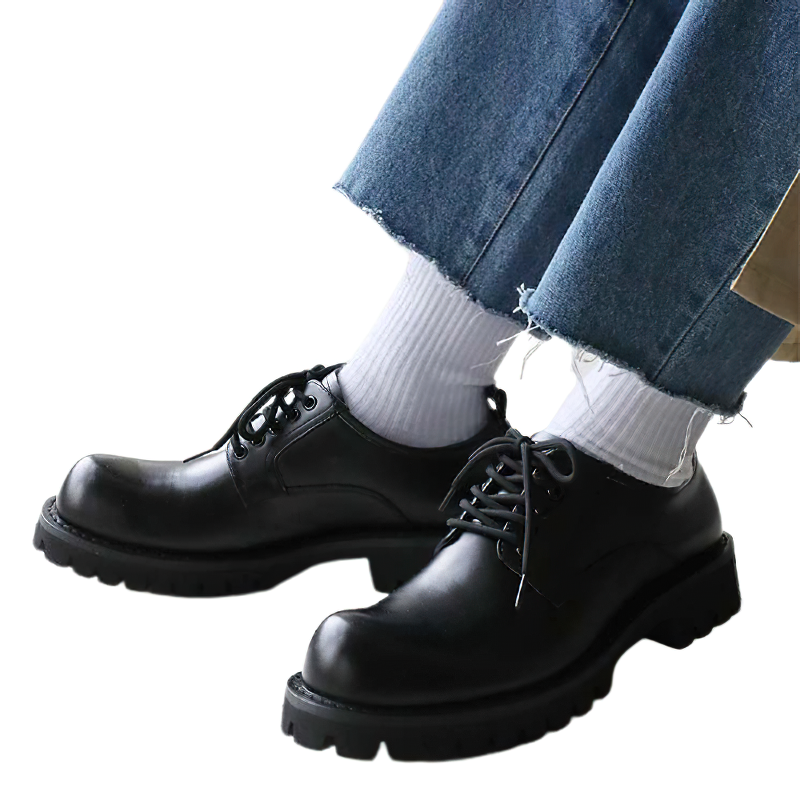Casual men's black leather shoes with platform soles, worn with denim jeans and white socks, stylish and fashionable footwear.