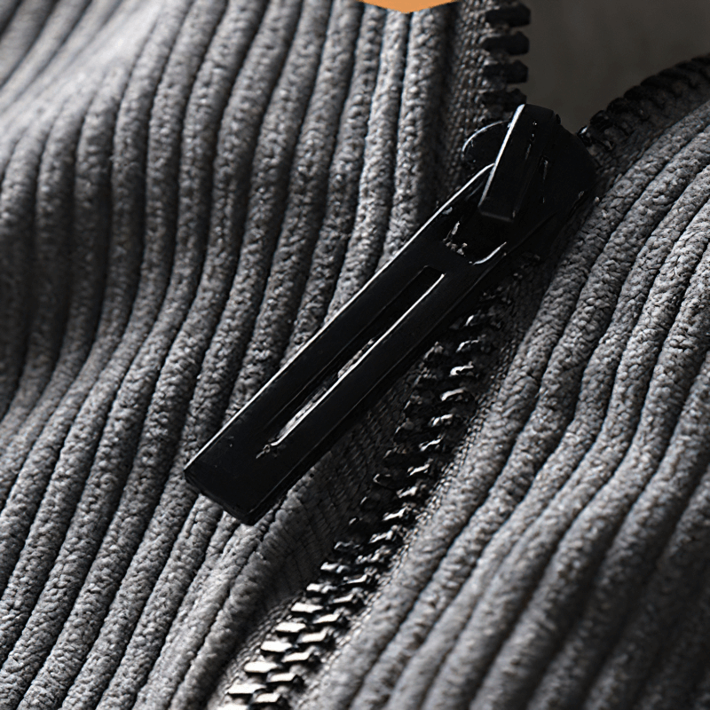 Close-up of the zipper on a casual solid color gray corduroy jacket with a textured fabric pattern.