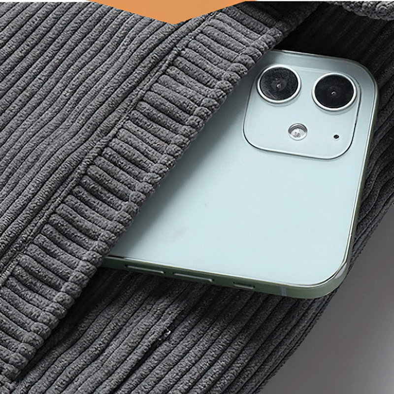 Close-up of a light green smartphone nestled in a cozy gray corduroy jacket.