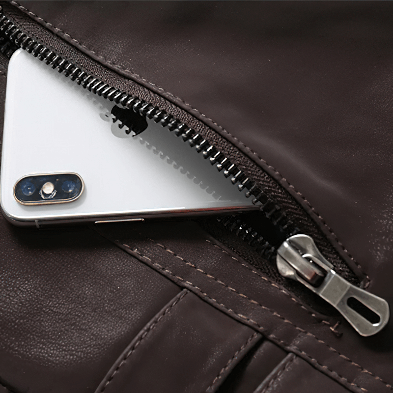 Close-up of a brown PU leather jacket zipper with a smartphone tucked inside, showcasing its multi-pocket design.