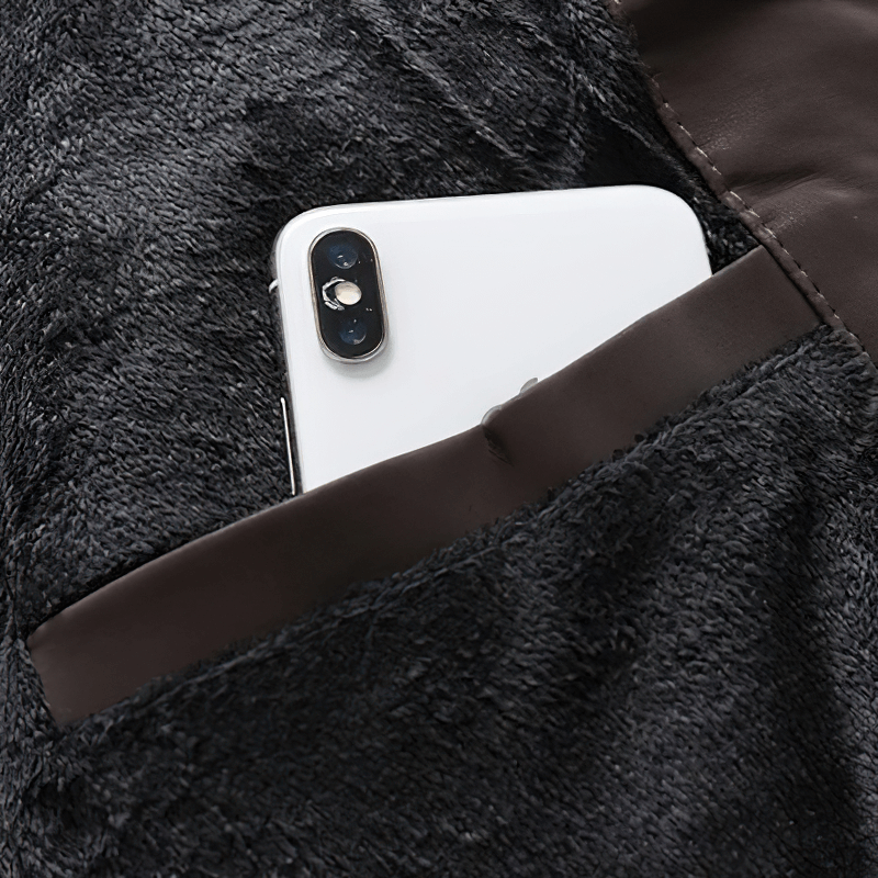 Close-up of a smartphone in the pocket of a men's PU leather motorcycle jacket.