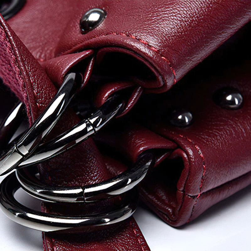 Close-up of a burgundy PU leather handbag showcasing stylish rings and studs, highlighting its exquisite design and craftsmanship.