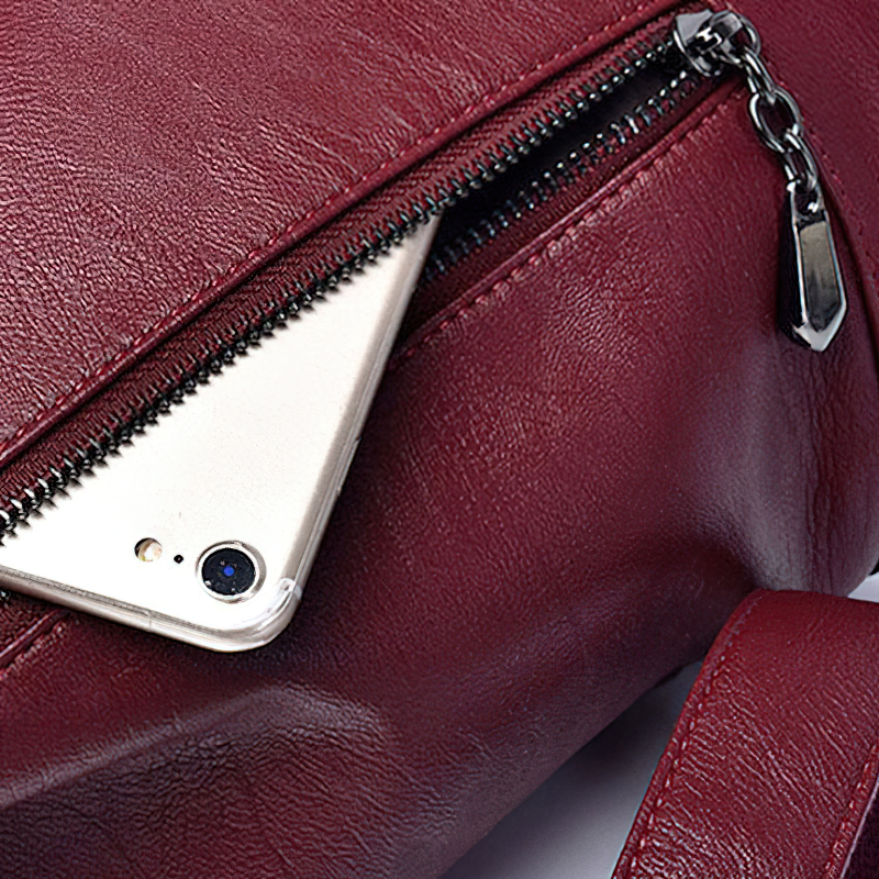 Close-up of a burgundy PU leather shoulder bag zipper with a smartphone partially inserted inside.