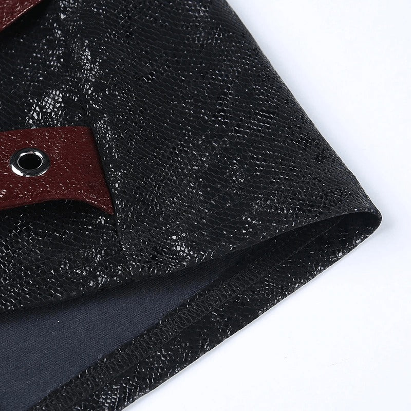 Close-up of the stylish texture of a black high-waisted mini skirt featuring rivet straps and rings.