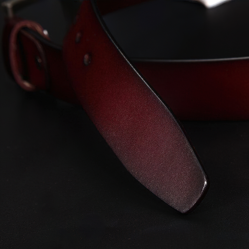 Close-up of a classic genuine leather belt for men in rich burgundy with a sleek metal buckle.