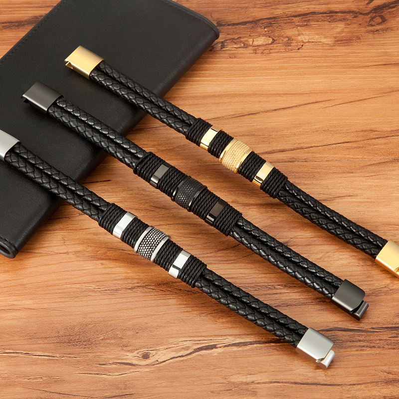 Three classic stainless steel men's genuine leather bracelets showcasing black and gold accents on a wooden surface.