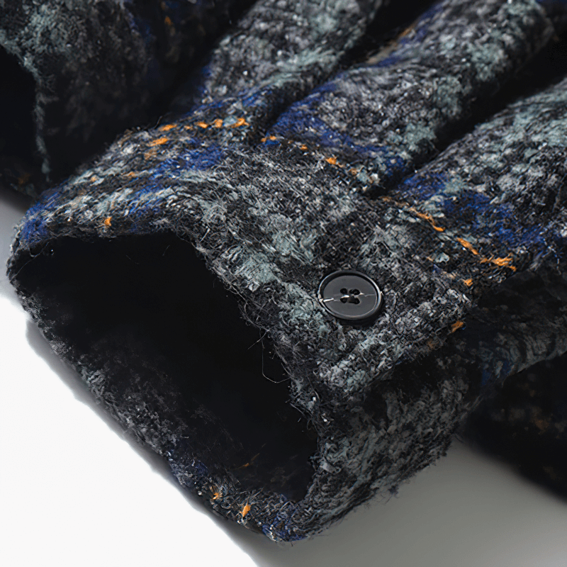 Close-up of the stylish cuff of a thick woolen plaid shirt for men, featuring a black button and textured fabric.