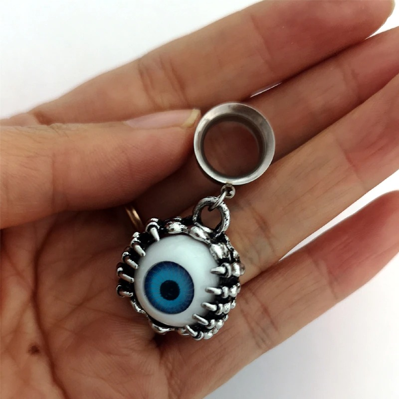 Unisex grunge-style stainless steel earring featuring an eyeball design in blue, held in a hand.