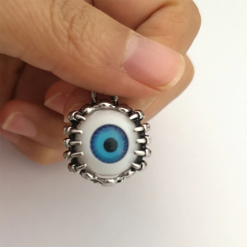 Unisex grunge-style stainless steel earring featuring a blue eyeball design, held by a hand.