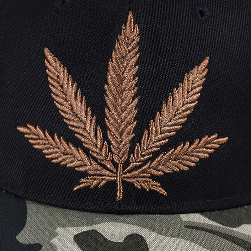Black cap featuring intricate bronze leaf embroidery and a stylish camo brim, perfect for casual outings.