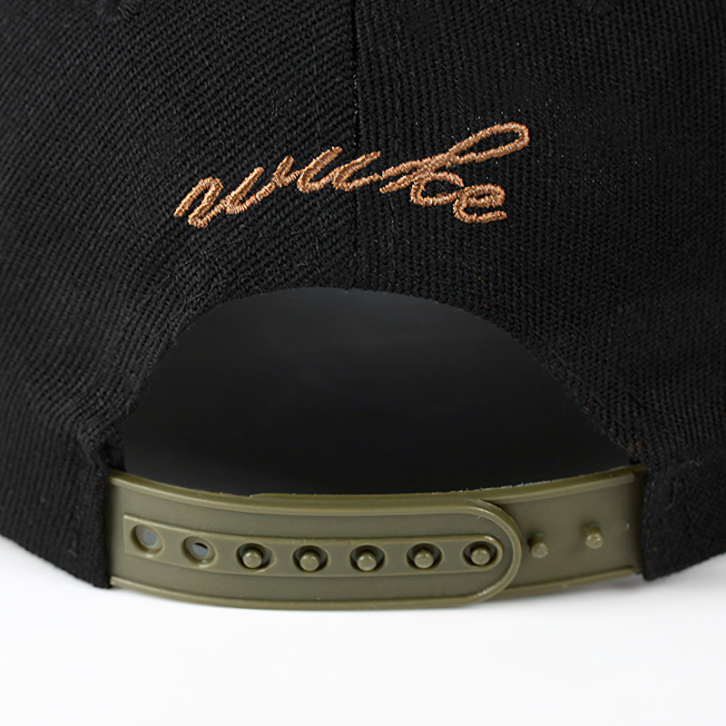 Close-up of the back of a black adjustable baseball cap with stylish brown embroidery and snap closure features.