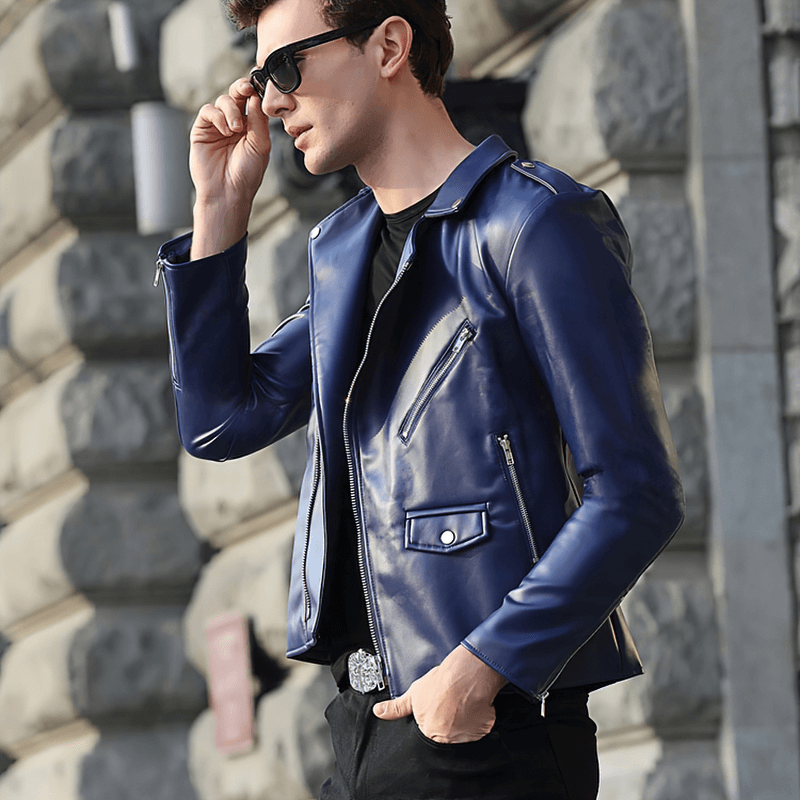 Fashionable young man in a blue faux leather biker jacket, accessorized with sunglasses, showcasing style and confidence.