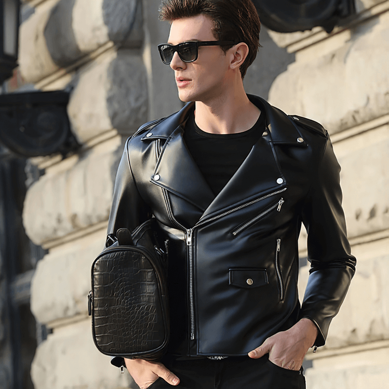 Stylish man wearing a black faux leather biker jacket with sunglasses, showcasing a trendy urban look.