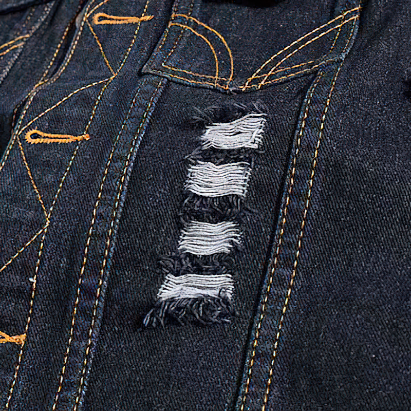 Close-up of ripped denim detailing on a men's sleeveless vest showcasing rock aesthetic style.