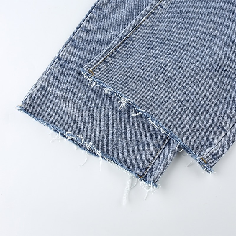 Close-up of frayed hem on cool high waist women's jeans, showcasing casual denim style with trendy details.