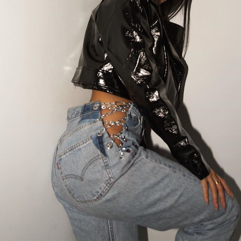 Trendy high waist woman's jeans with chains, styled casually with a sleek black crop top.