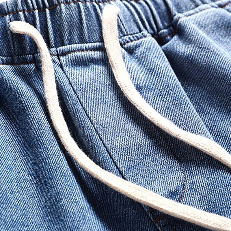 Close-up of cool loose denim shorts for men showcasing drawstrings and fabric texture.