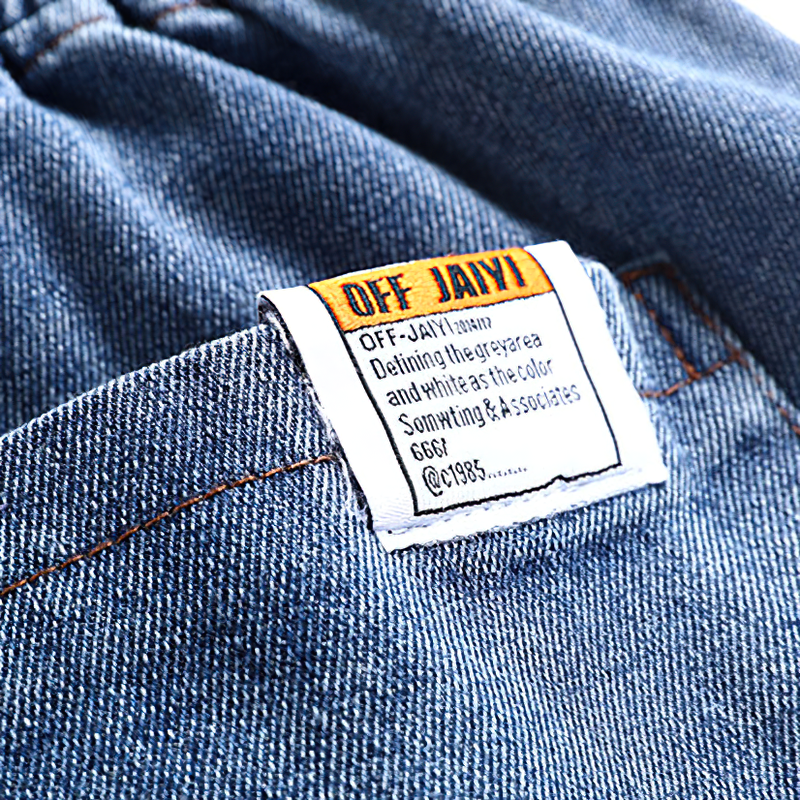 Close-up of a tag on denim shorts, showcasing the brand name and design details for trendy men's fashion.