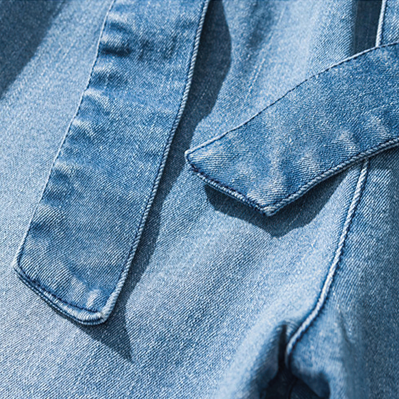 Close-up of cool loose jeans for men showing denim fabric and unique ribbon detail for retro joggers style.