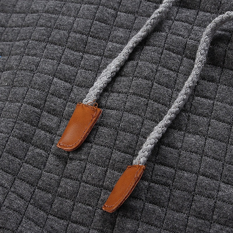 Close-up of gray polyester hoodie with textured pattern and stylish drawstrings for a rugged look.