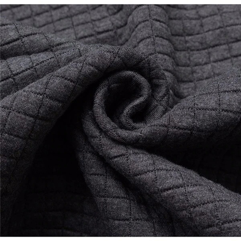 Close-up of textured dark gray fabric, showcasing the intricate pattern of the material ideal for a stylish hoodie.