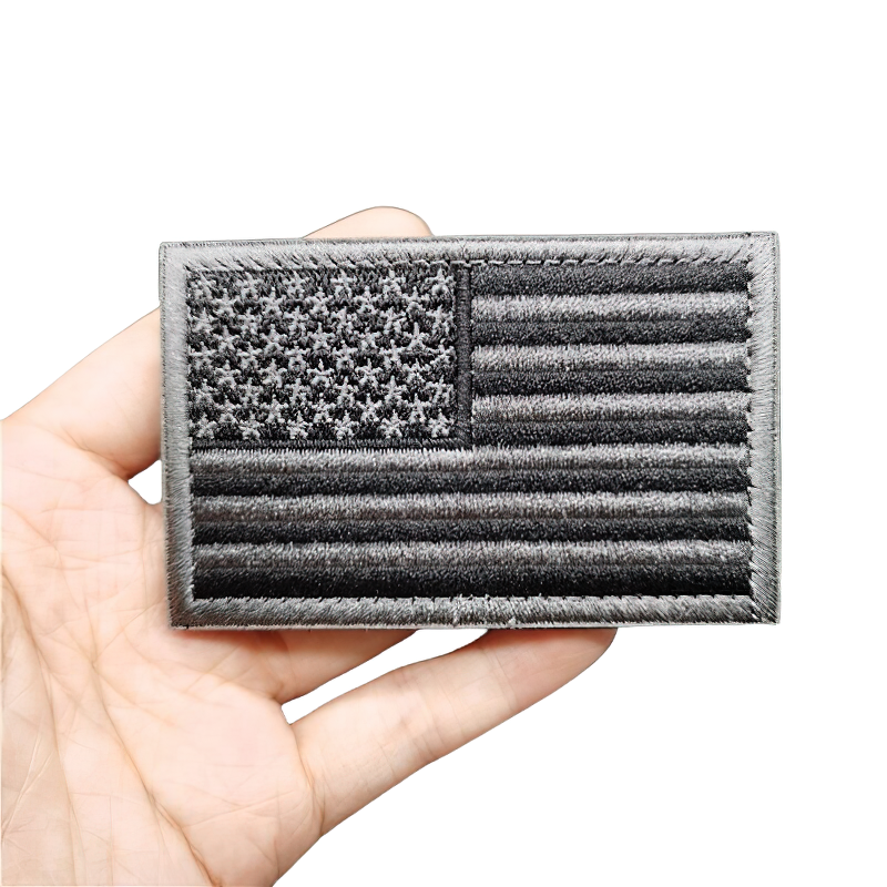 Hand holding a cool vintage military patch featuring a black embroidered American flag, perfect for unisex styling.