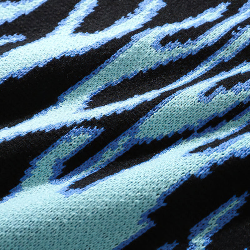 Close-up of a cool retro sweater featuring striking blue flame patterns on a black background.