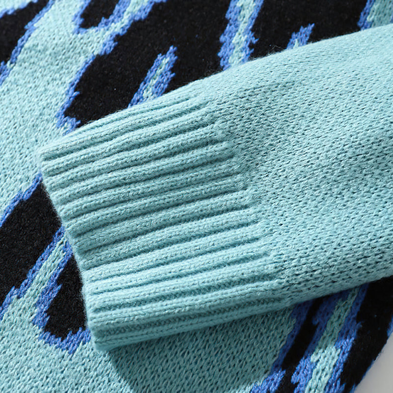 Close-up of the Cool Retro Sweater's sleeve with blue flame pattern in black and turquoise wool fabric.