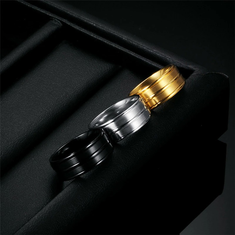 Three cool stainless steel unisex rings in black, silver, and gold, showcasing modern fashion jewelry styles.
