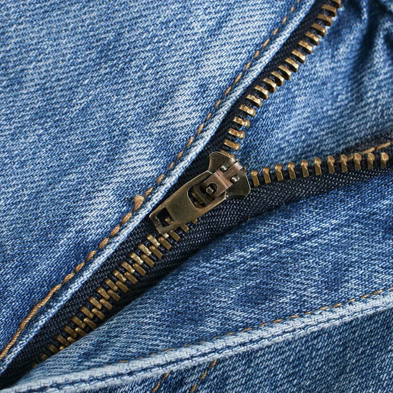 Close-up of zipper detail on cool women's high waist wide leg denim pants with pockets.