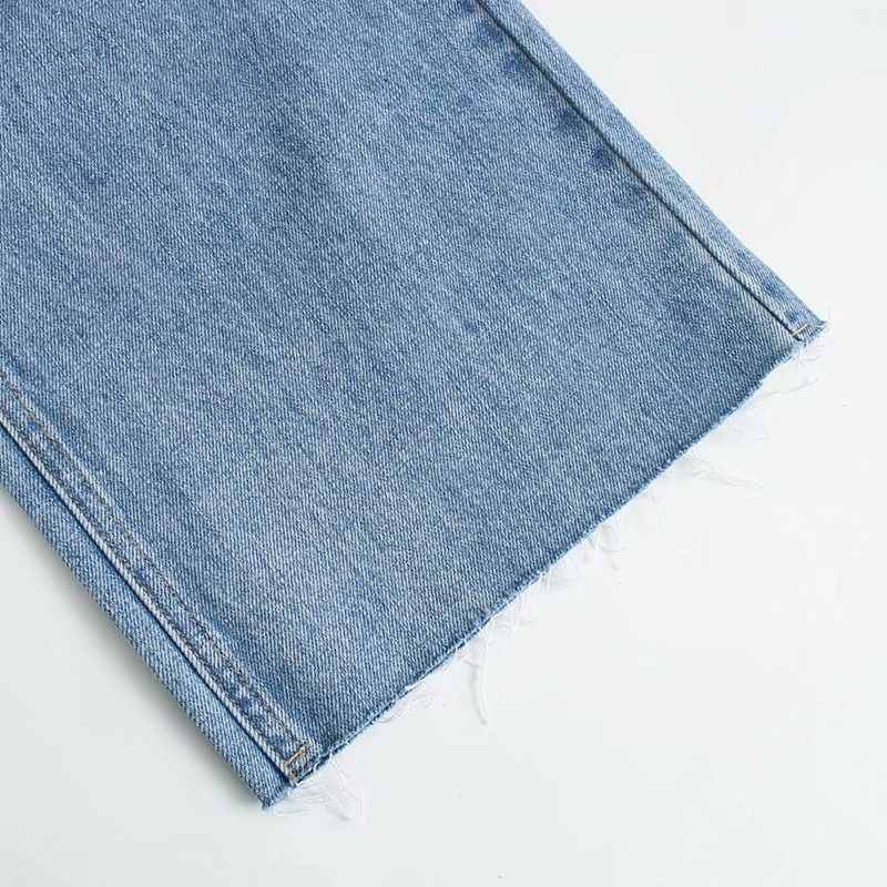 Close-up of the hem of cool wide-leg high waist denim jeans in light blue with frayed edges.