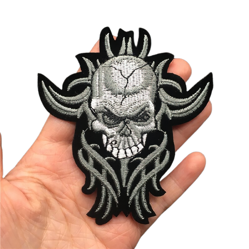 Cracked skull iron-on patch in hand, stylish rock accessory for clothing, unisex embroidered design.