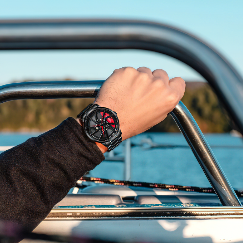 Stylish male hand wearing a waterproof 3D watch with a wheel design, gripping a boat railing against a scenic backdrop.