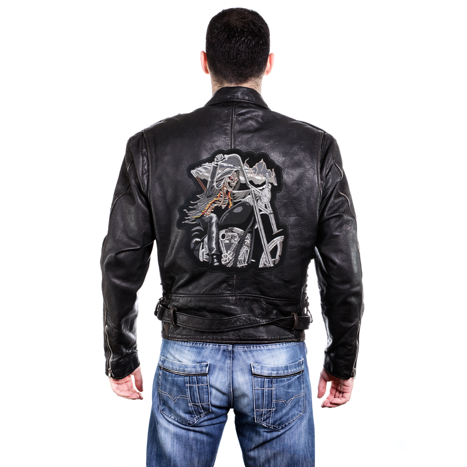Man wearing a black leather jacket featuring a large embroidered skeleton biker patch on the back.