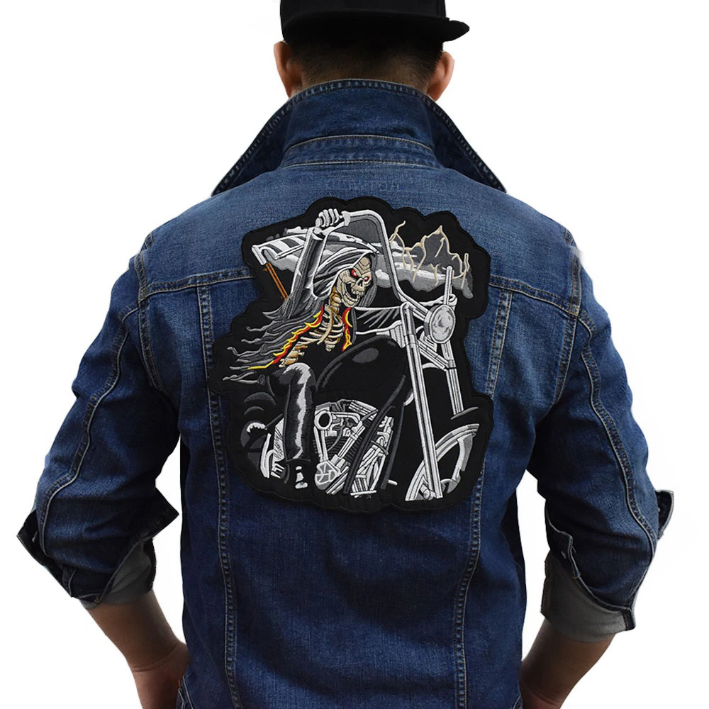 Creepy skull biker patch on the back of a denim jacket, showcasing an embroidered skeleton riding a motorcycle.