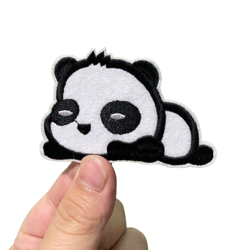 Cute sleeping panda patch held by a hand, stylish unisex embroidery for clothing, perfect animal decal for fashion.
