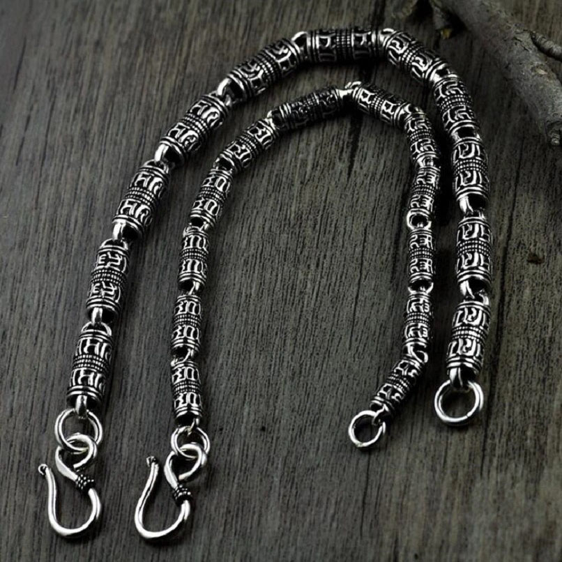 Cylindrical silver bracelet featuring intricate carved symbols, perfect for ethnic jewelry lovers.