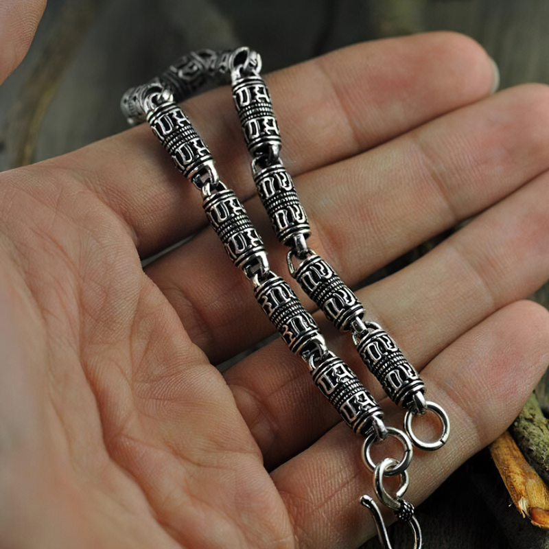 Cylindrical 925 silver bracelet with engraved symbols, showcased in a hand, perfect for ethnic jewelry lovers.