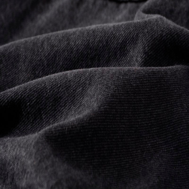 Close-up of soft black denim fabric showcasing its texture and weave, perfect for punk and streetwear fashion.