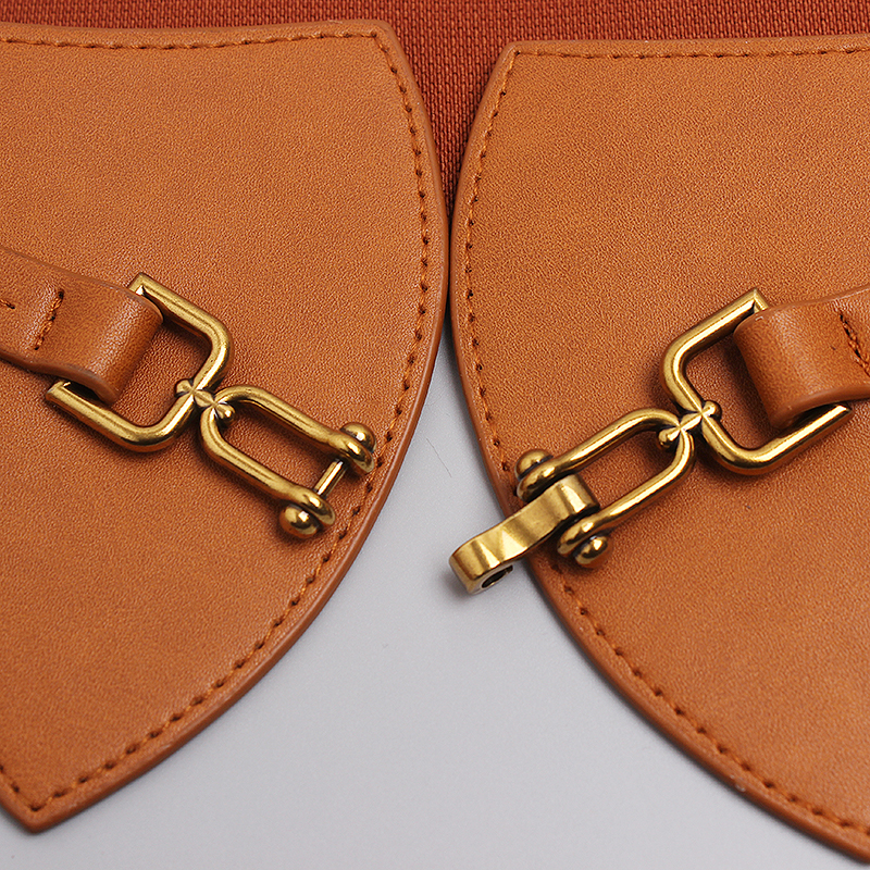 Close-up of designer PU leather wide belt with brass metal clasps, showcasing vintage fashion detail.