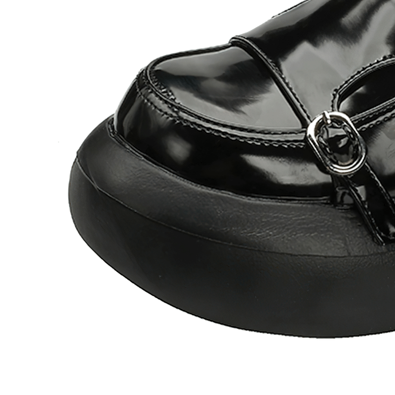 Close-up of black patent leather loafers with buckles in punk style, showcasing sleek design and shiny finish.