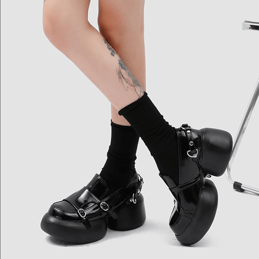 Black patent leather loafers with buckles, punk style shoes worn with black socks.