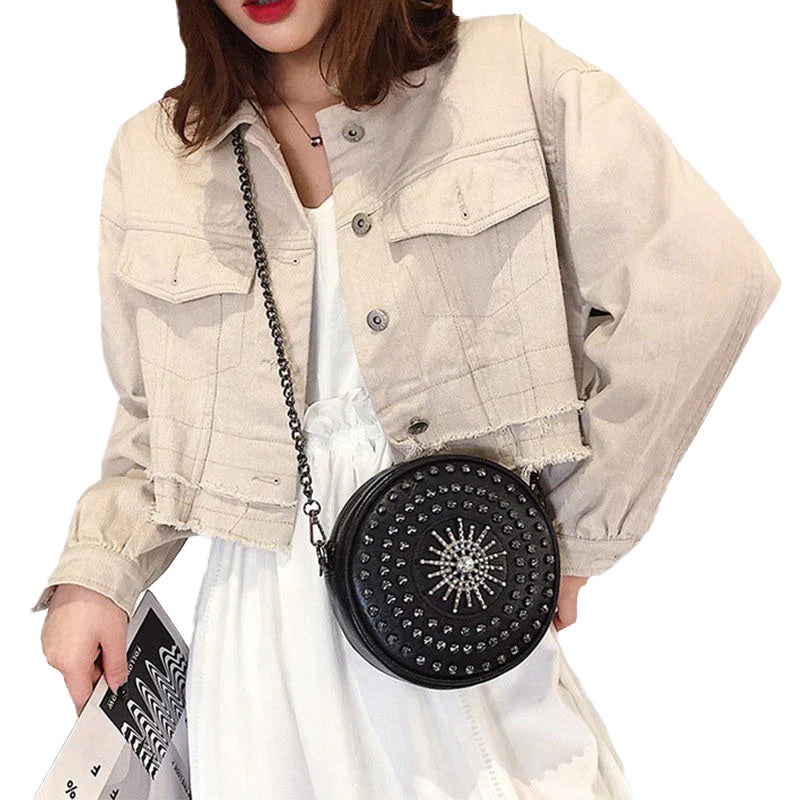 Stylish woman in a cropped jacket holds a round black diamond-studded bag, showcasing rock fashion vibes.