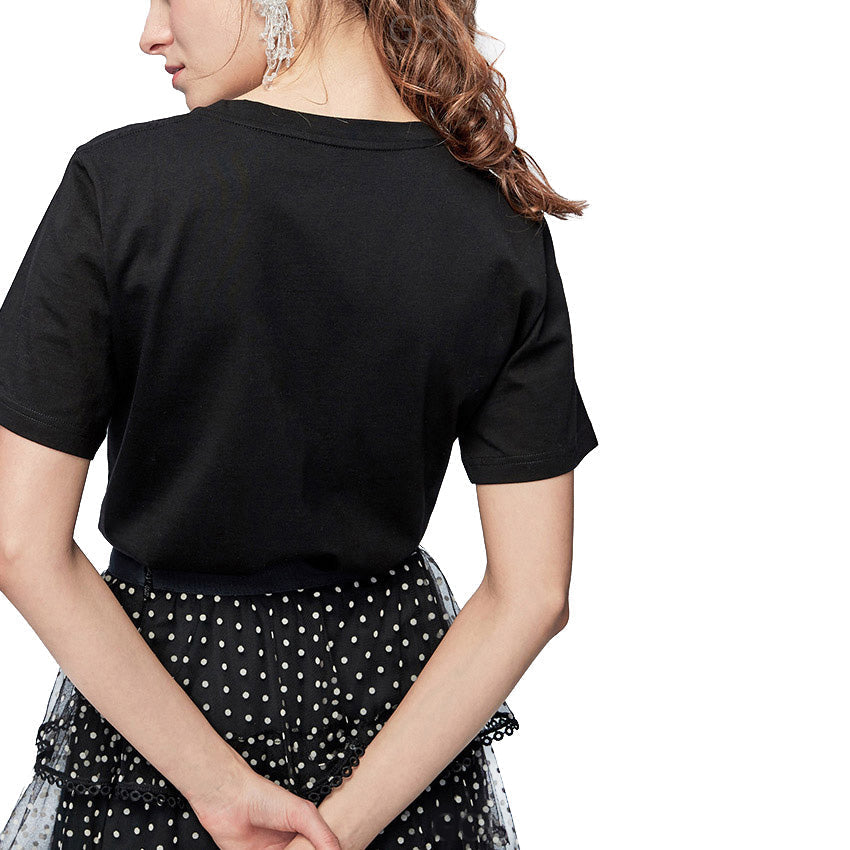 Back view of a woman wearing a black loose rock T-shirt paired with a polka dot skirt, showcasing effortless style.