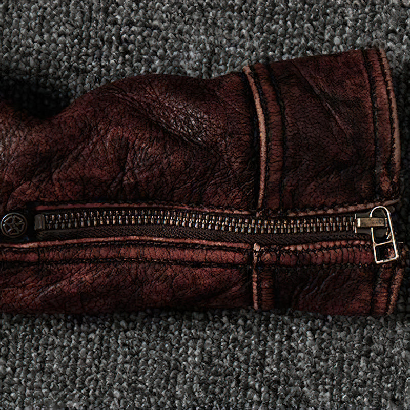 Close-up of the zipper on a durable brown biker jacket made from genuine leather, showcasing vintage style and texture.