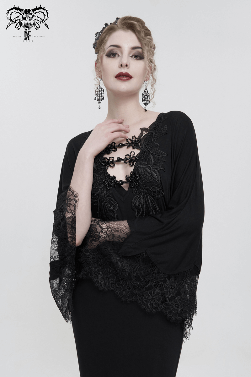 Elegant woman in black lace mermaid dress with cape sleeves, showcasing gothic style and sophisticated fashion.