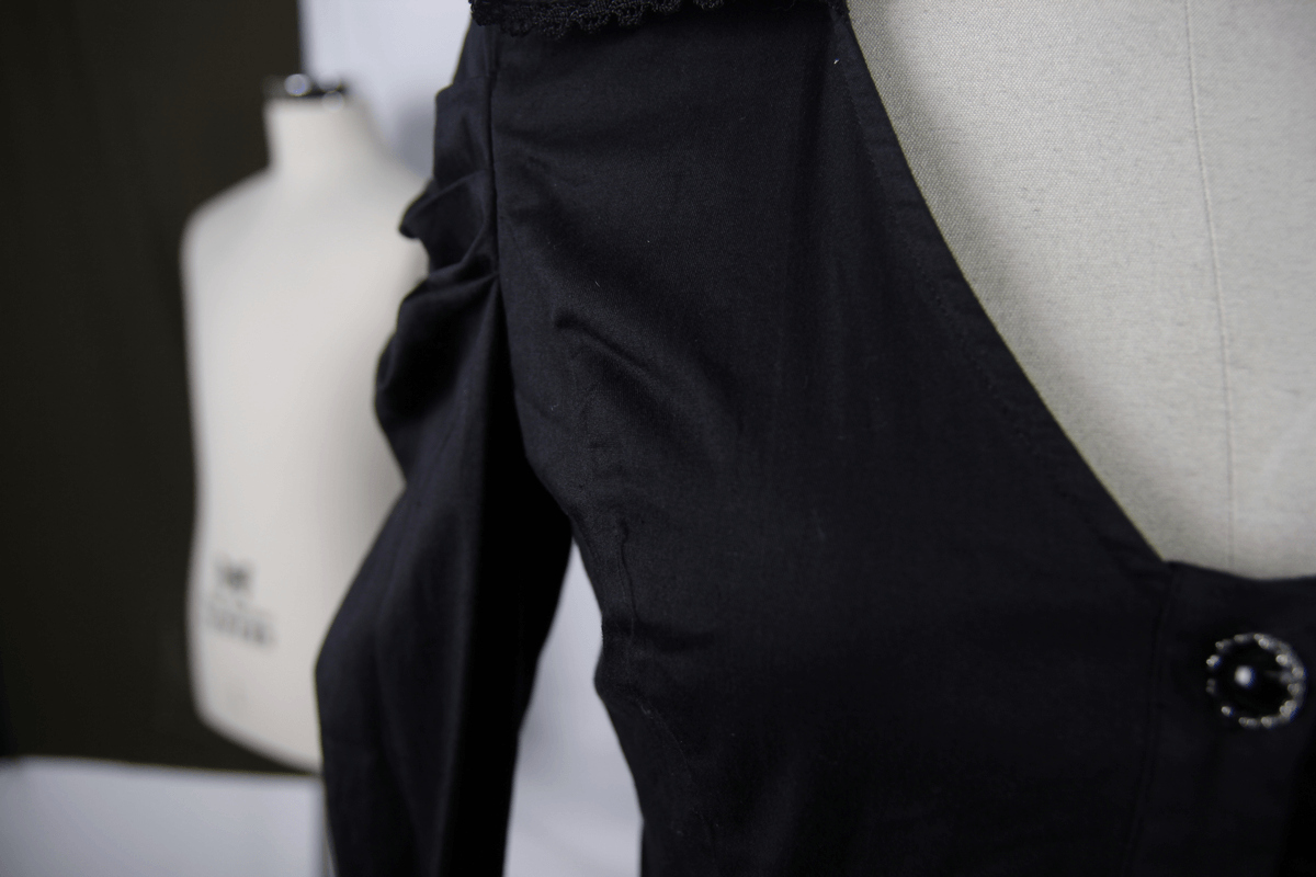 Close-up of an elegant black gothic shirt featuring a stylish button and delicate design.